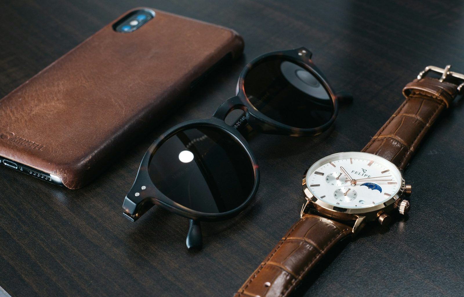 black framed sunglasses beside brown leather case