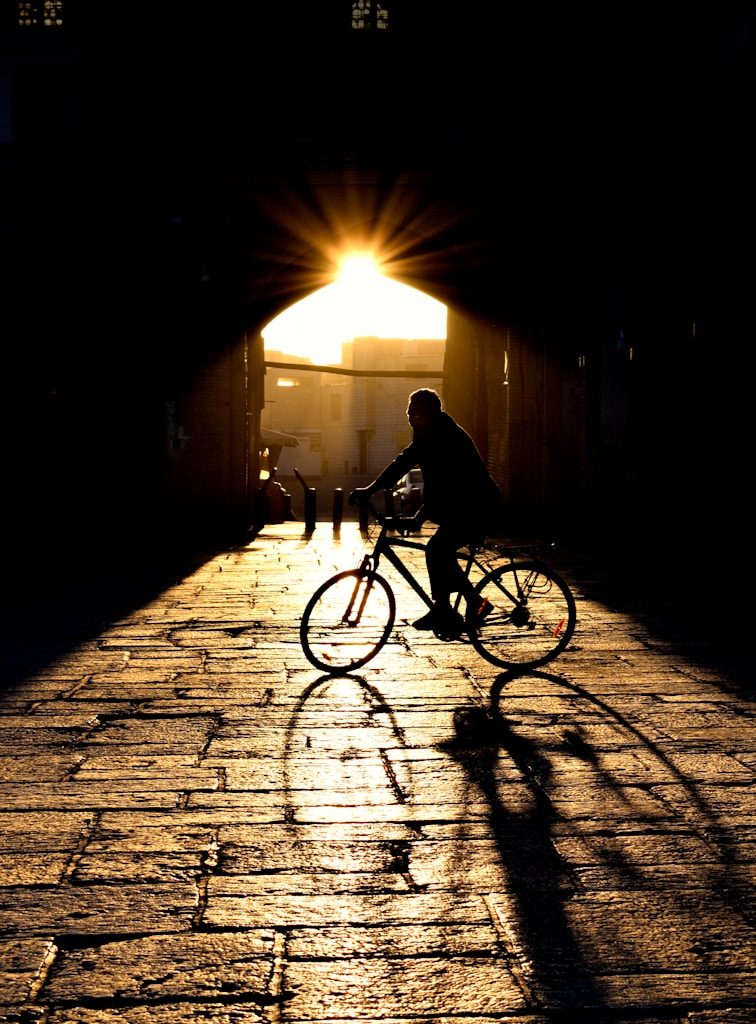 a man riding a bike down a street under a bridge