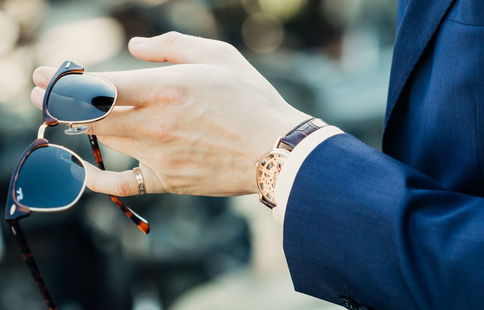 shallow focus photography of man holding sunglasses