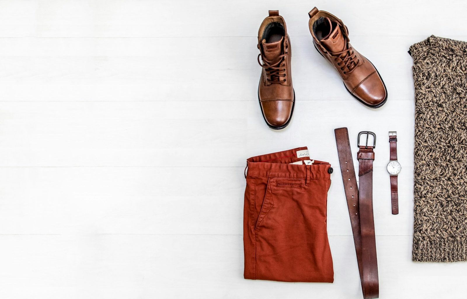 pair of brown leather boots, red shorts, brown leather belt, round gold-colored watch, and brown top