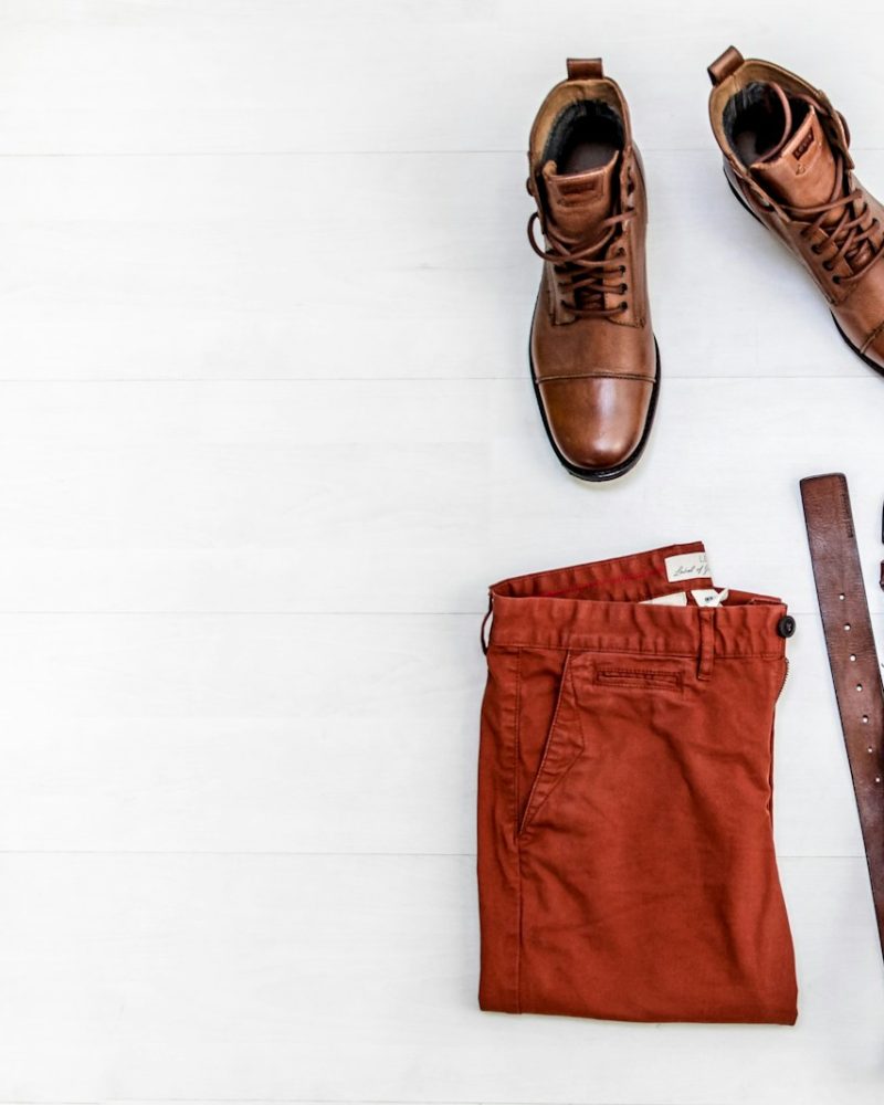 pair of brown leather boots, red shorts, brown leather belt, round gold-colored watch, and brown top