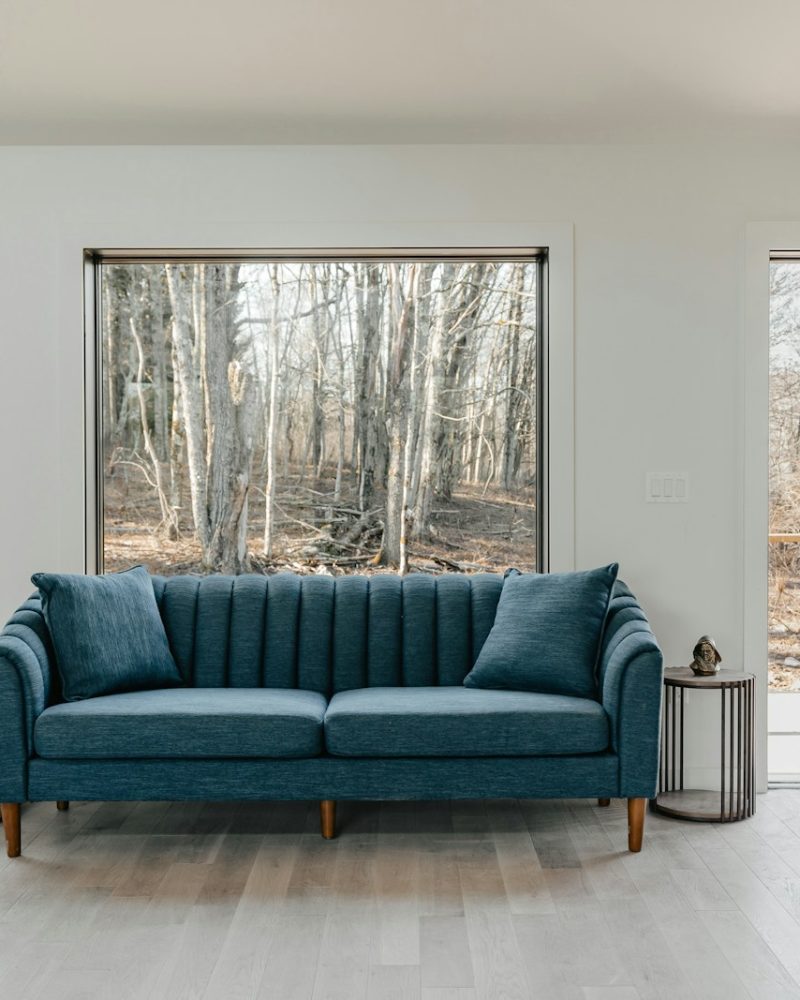 a blue couch sitting in a living room next to two windows