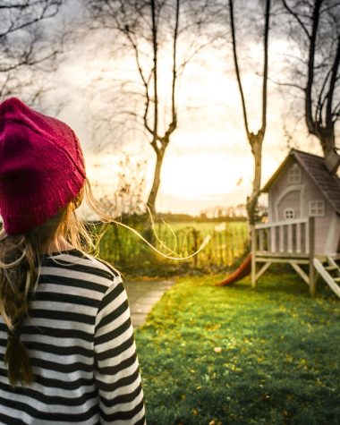 Houten speeltoestel in een groene tuin met glijbaan en klimwand